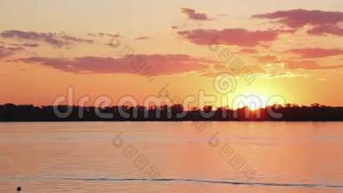 在美丽的橙色日落时，可以看到湖、海岸线、漂浮的船只的时间推移。